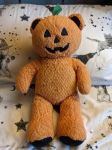 An orange teddy bear with a pumpkin face.